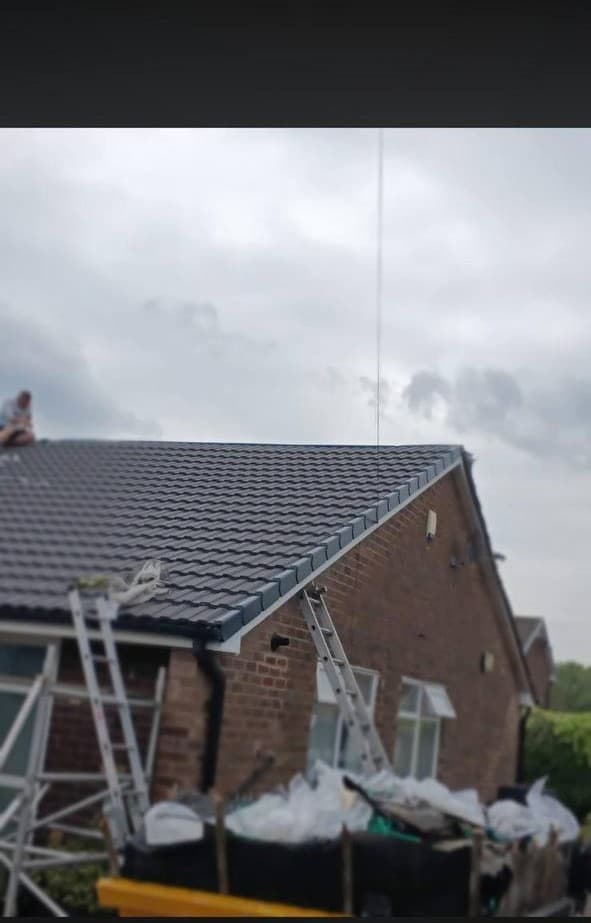 A completed reroof on a brick bungalow, with the stripped tiles bagged up ready to be taken away