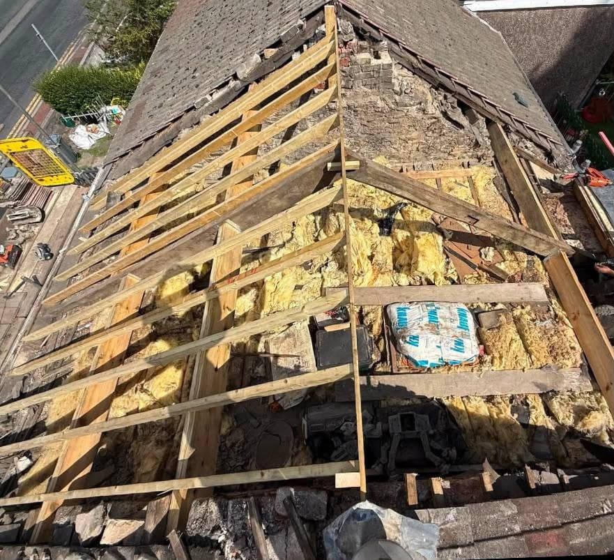 A roof stripped back to the rafters with new battens going on, seen from above