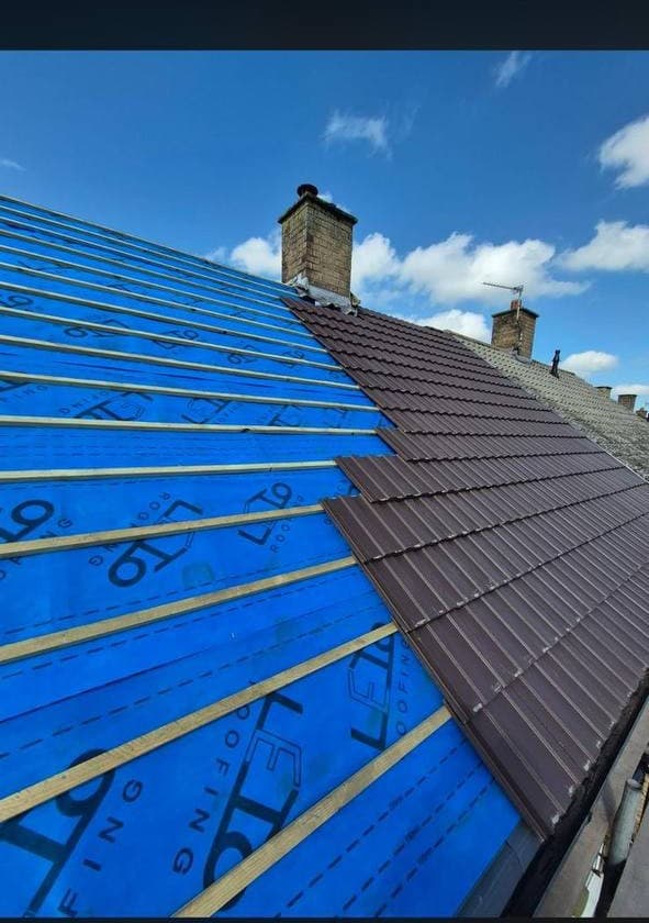 New tiles being laid in courses over blue breather membrane and treated battens