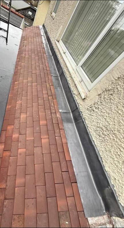 A new lean-to roof in plain tiles, with lead dressed up the wall abutment beside it