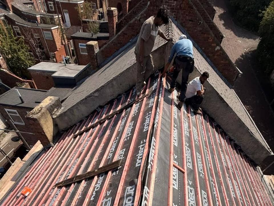 Three Midlands Roofing roofers working at the ridge of a reroof
